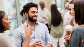 Internationale Alumni stehen zusammen und unterhalten sich lachend.