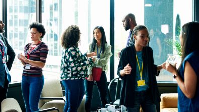 Internationale Alumni stehen auf einer Veranstaltung in Gruppen zusammen und unterhalten sich.